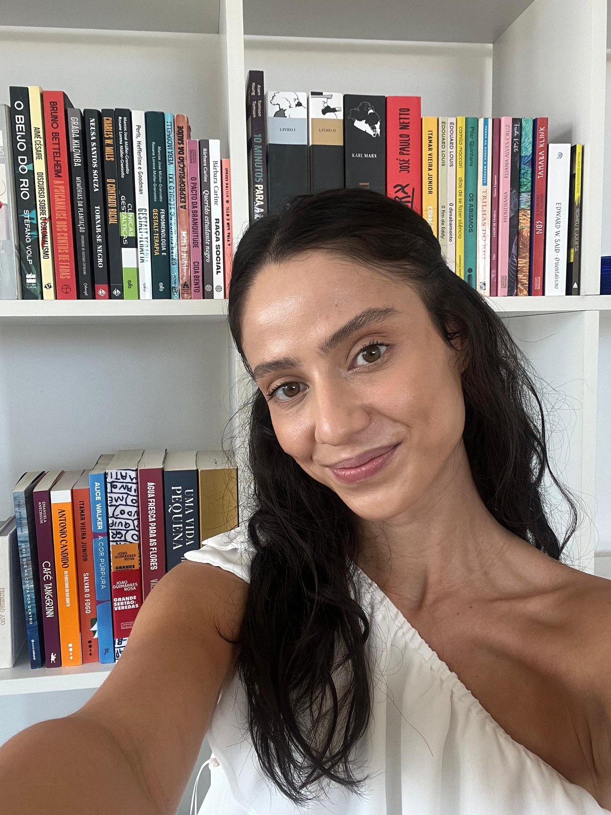 Mariana Amaral em frente à sua estante de livros